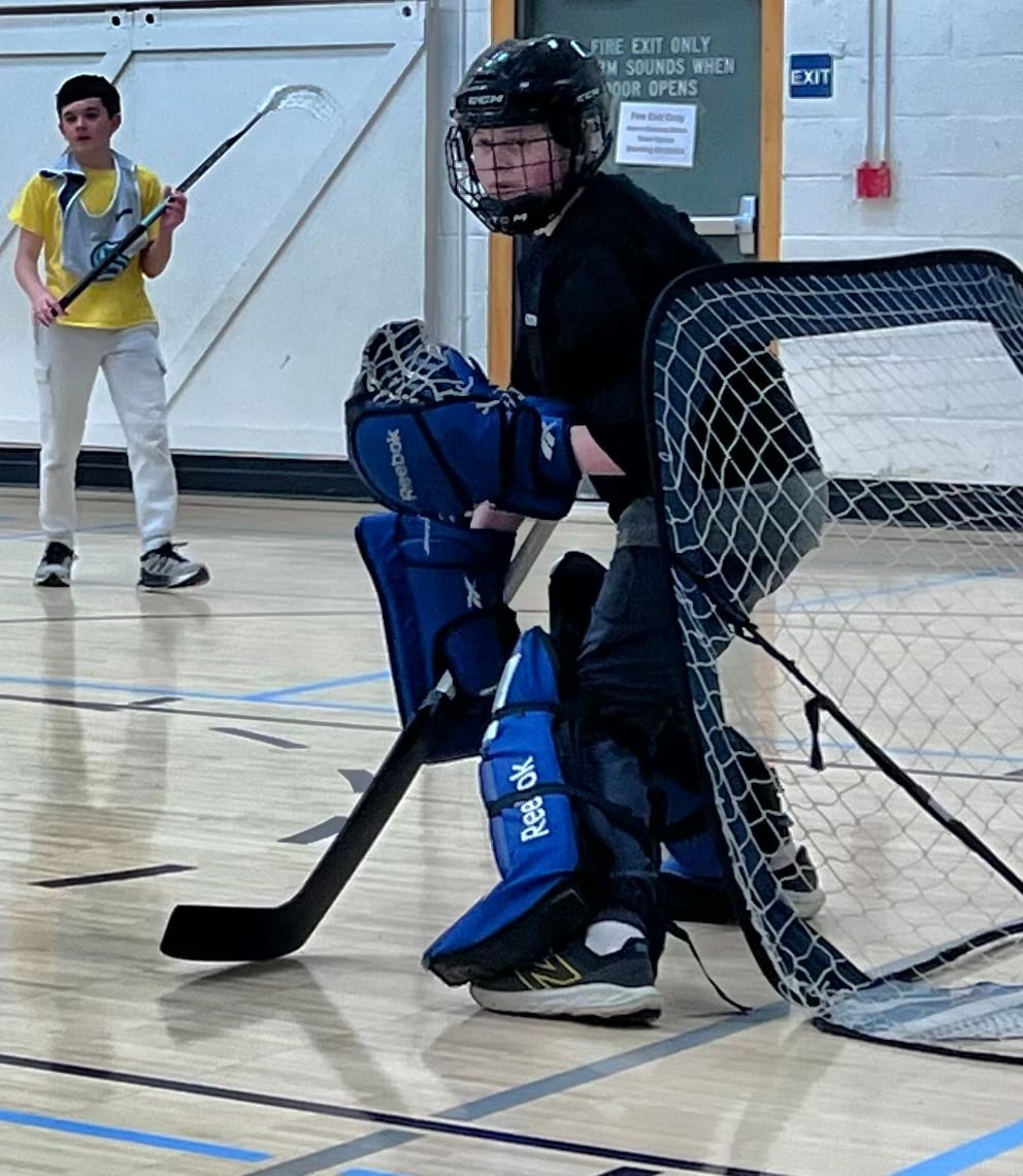 A young goalie in full pads guarding the net