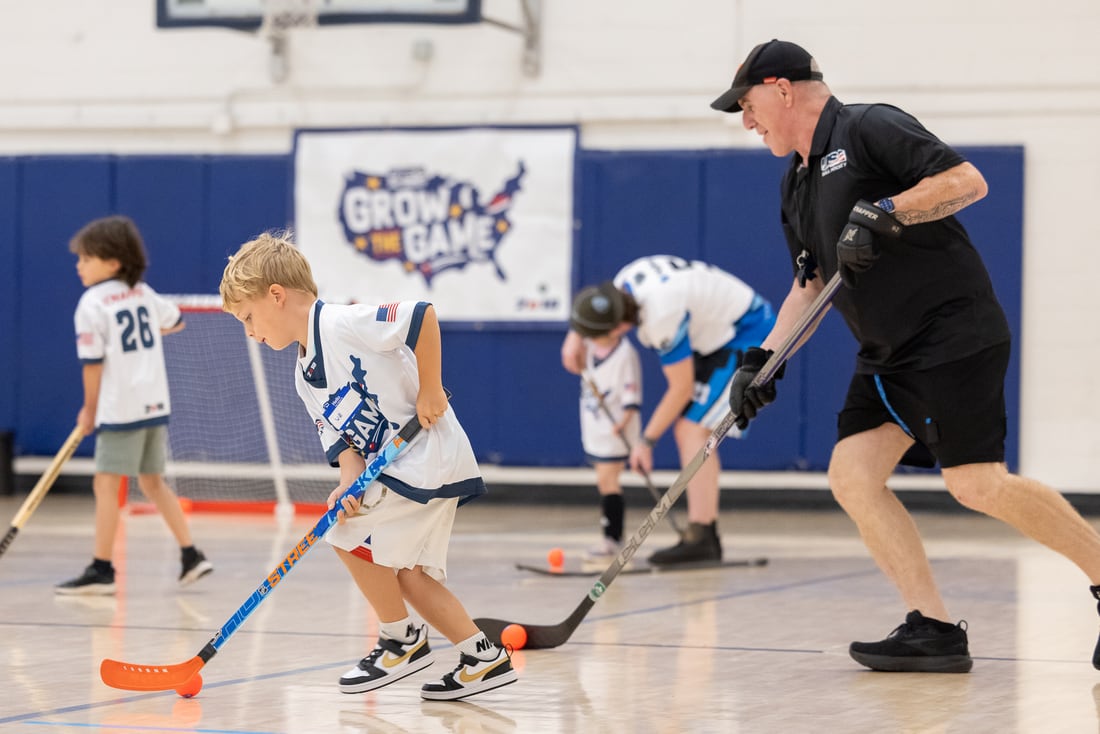 A coach guides our youngest players on the floor