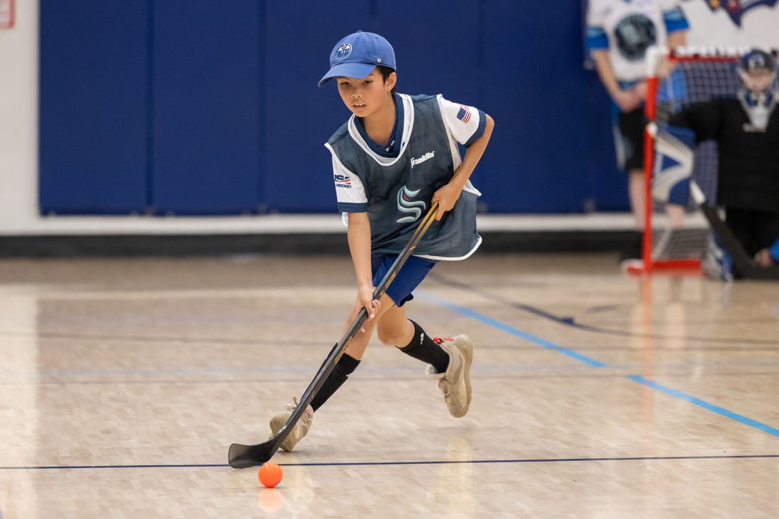 A young player stickhandles up the floor in full stride