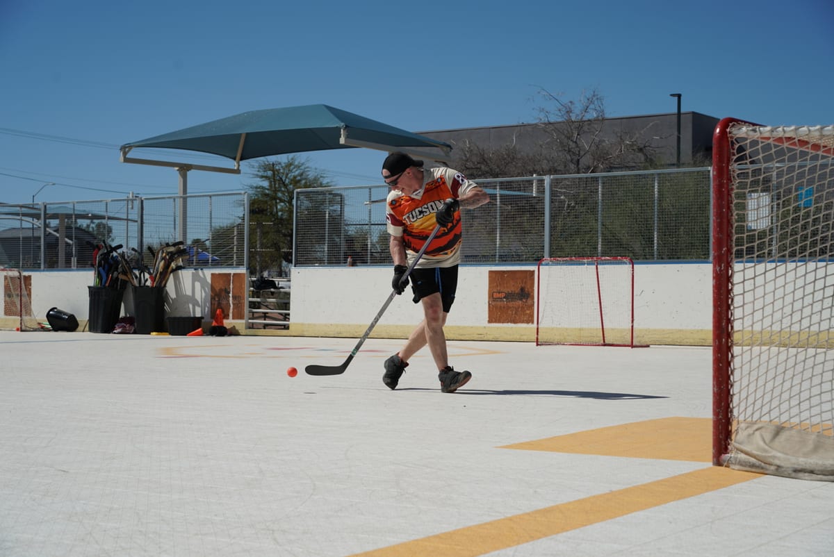Ball hockey player taking a shot on an outdoor rink at a Grow the Game day